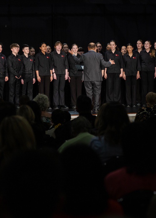 A school choir performs under their conductor's direction.